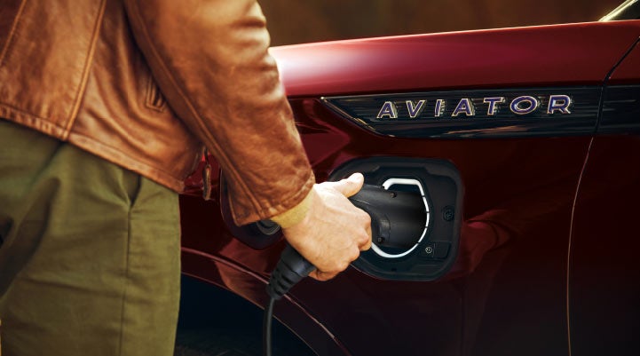 A hand is shown plugging in the charger into the charging port of a 2021 Lincoln Aviator | Pierre Lincoln in Lynnwood WA